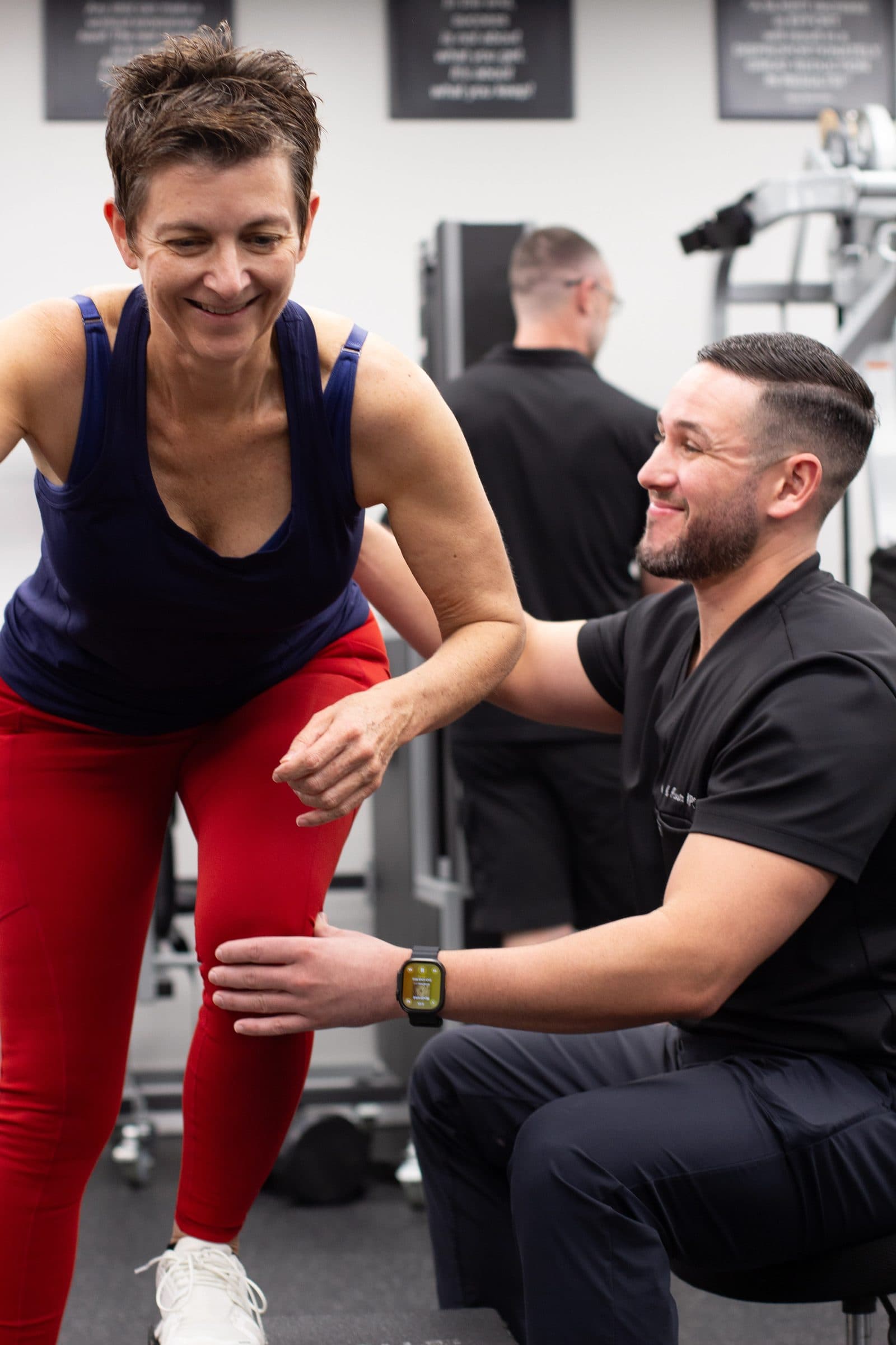 Dr. Nicholas Acosta coaching a smiling patient through a hip hinge in the clinic gym