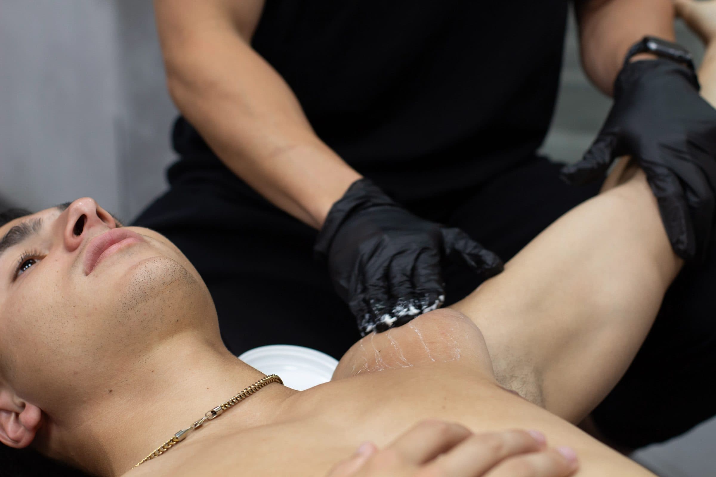 Gloved hands working the soft tissue of a patient's chest and shoulder on the treatment table